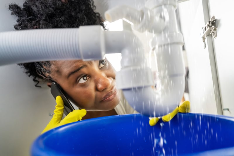 Technician working on leaking pipe under sink.