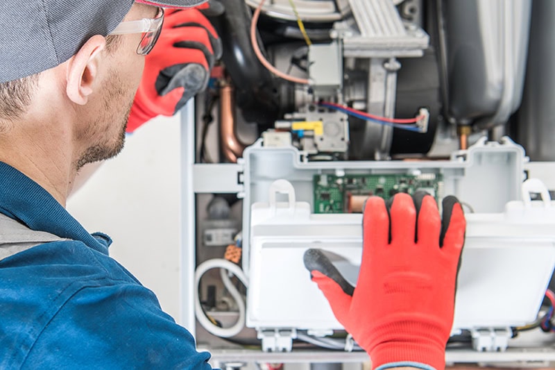 Schedule Your Annual Furnace Inspection Now. Heating Central Gas Furnace Issue. Technician Trying To Fix the Problem with the Residential Heating Equipment.
